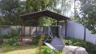 Навес двускатный из коричневого профнастила для зоны отдыха на даче